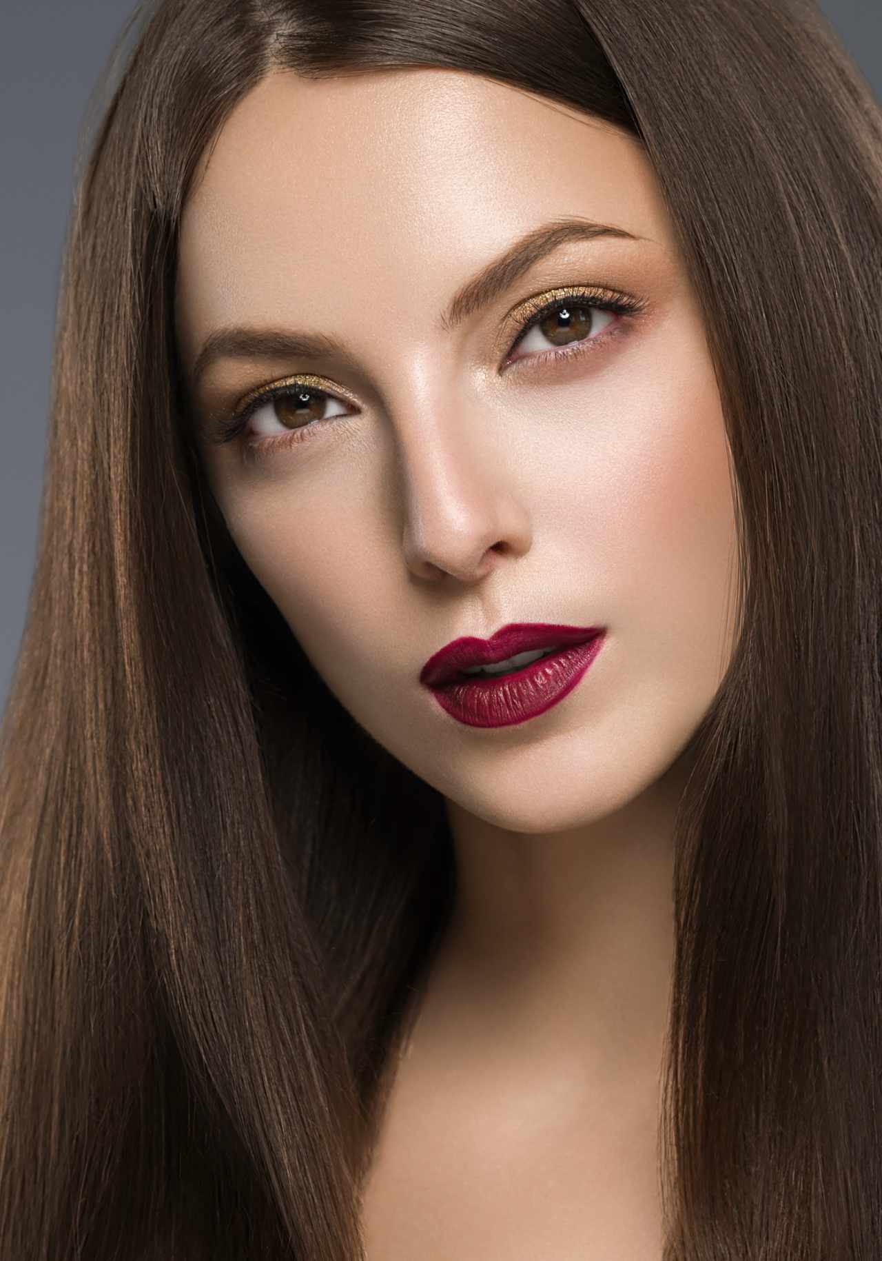 a woman with smooth brown hair and matte berry lipstick showcasing long-lasting color