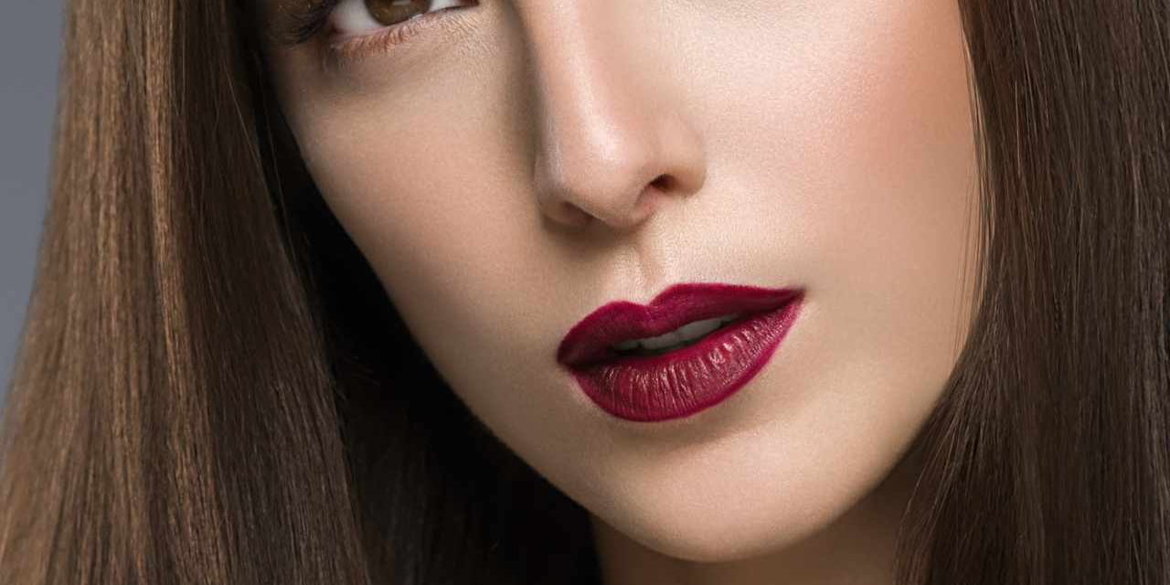 a woman with smooth brown hair and matte berry lipstick showcasing long-lasting color