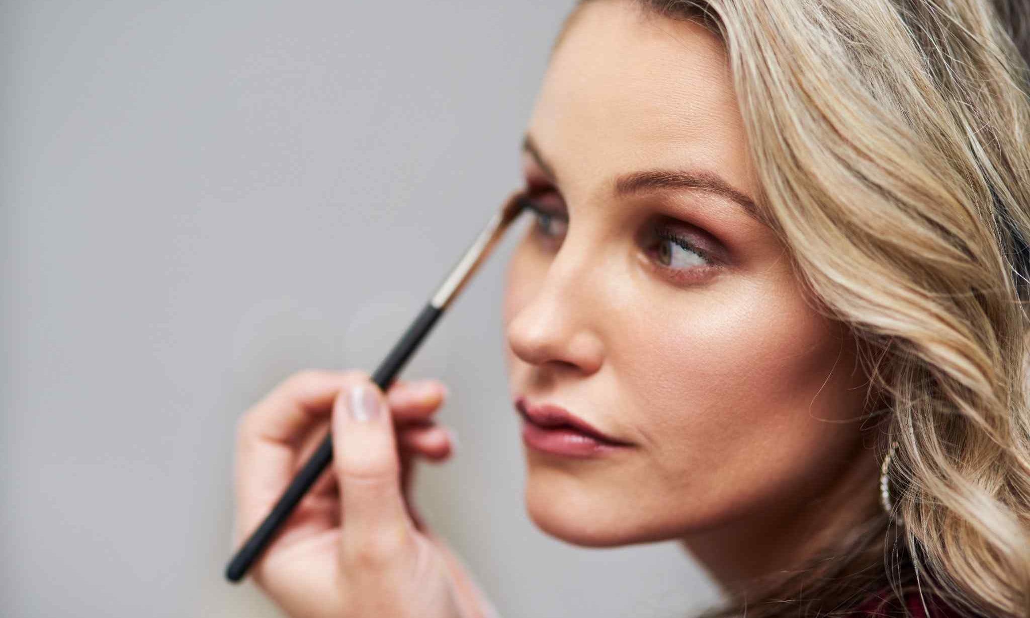 mature woman applying creamy eyeshadow