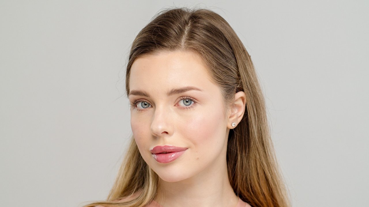 model with natural makeup wearing soft pink sheer lipstick and smooth glowing skin
