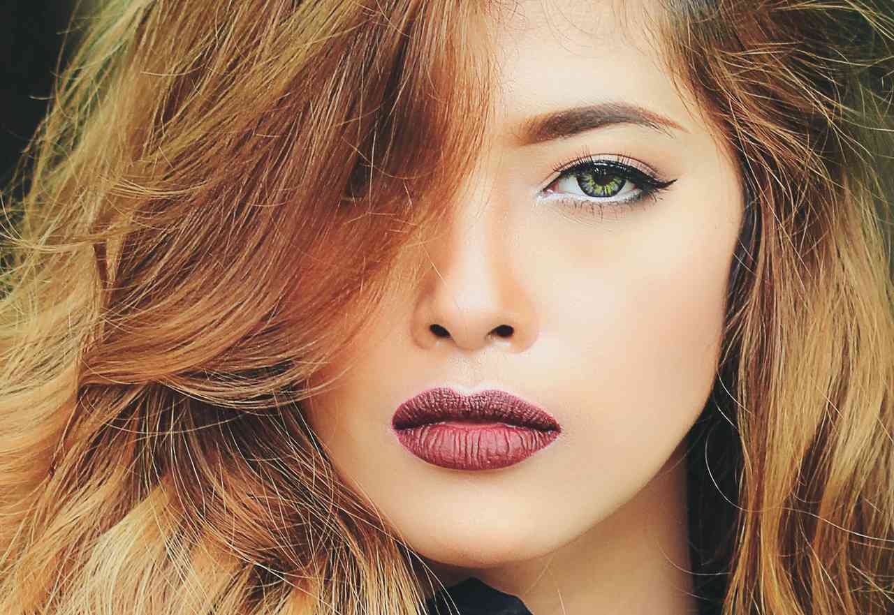 woman with warm golden-brown hair, green eyes, and deep rose lipstick