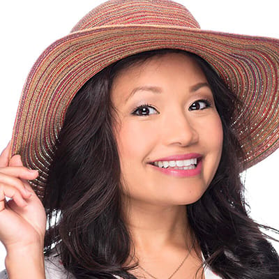 Image of lady with medium skin tone and long black hair and dark eyes wearing a summer hat. She is wearing lipstick in the shade called Let's Flamingle by Red Apple Lipstick. Let’s Flamingle is a tropical hot pink with a coral cast. While this lipstick is a hot pink, it’s on the softer side, making this sweet and sassy lipstick more versatile and not overly bright.