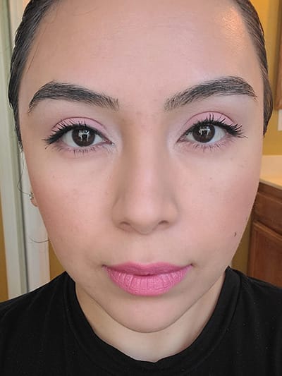 Image of female with light to medium skin tone, Black Hair, Dark eyebrows and dark brown eyes. Pink shades for eyeshadows, Pink shades of blush on her cheeks and Mauve Me Lipstick 