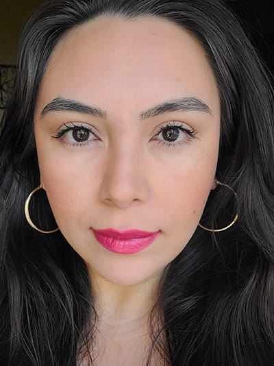 Image of lady with long dark hair, dark brows and eyes and medium skin tone. She is wearing Hibiscus lipstick, Gotta Glow Blush with Porcelain and Sundrop Bronzer on the eyelids by Red Apple Lipstick 