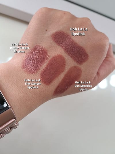 Image of back of hand model with lipstick swatches showing Ooh La La Lipstick alone, then Ooh La La with Honey Badger Gloss over it, then Ooh La La with Tiny Dancer and Ooh La La with Sun Sparkles