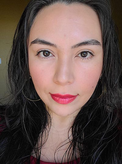 Image of lady with long black hair, dark eyes wearing Sundrop Bronzer, Gotta Glow blush, The Lash Project mascara and Risque Lipstick all by Red Apple Lipstick 