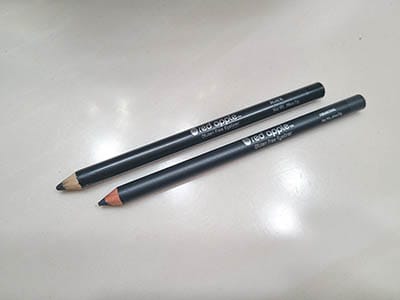 Image of the Black and Charcoal eyeliner pencils by Red Apple Lipstick. Both are laying side by side with the cap off and pencil tip sharpened. 