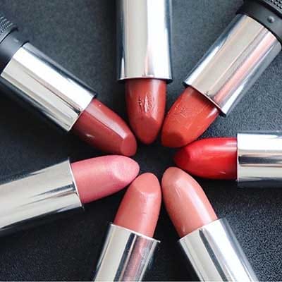 Image of 7 Red Apple Lipstick tubes with bullet's twisted up and caps off laying in a circular pattern showcasing some colors that would make a great cream blush if preferred 